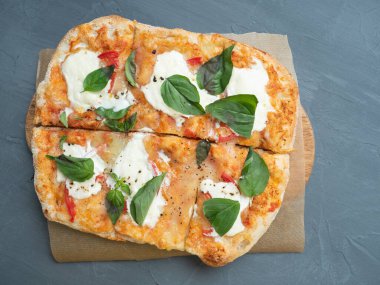 Gri arka planda peynirli ve otlu lezzetli, çıtır çıtır Roma pizzası. El işi kâğıdı, keten peçete. Üst manzara, düz uzanma