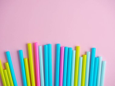 Pembe kağıt arka planda çok renkli plastik tüplerin yakın plan çekimi. Üst manzara, düz uzanma