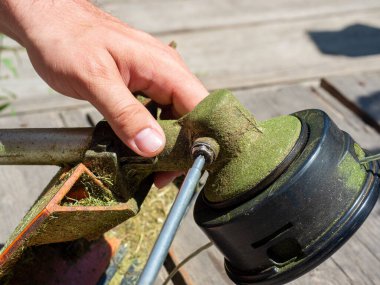 Çim biçme makinesinin vites kutusundaki vidayı sökmeye yakın plan. Ekipmanların bakımı