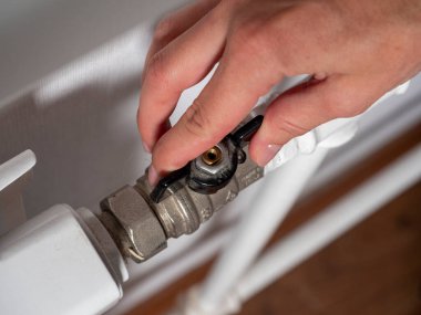 Merkezi ısıtma bataryasının kapağında bir kadın eli var. Isı çakışması konsepti, enerji taşıyıcılarının krizi.