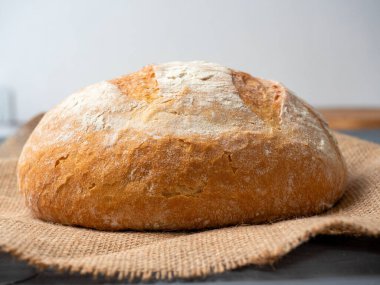 Koyu bir arka planda taze gevrek, yuvarlak buğday ekmeği yakın plan. Yan görünüm