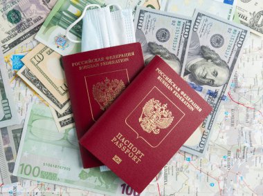 Dolar ve avro banknotlarında iki Rus pasaportu var. Pasaportlardan birine tıbbi maske takılmış. Salgın ve hastalıklar sırasında seyahat etme kavramı. Üst manzara, düz uzanma