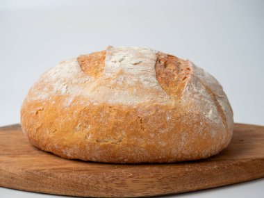 Ahşap tepside taze pişmiş, çıtır çıtır bir kabuklu buğday ekmeği duruyor. Yan görünüm, fırın konsepti