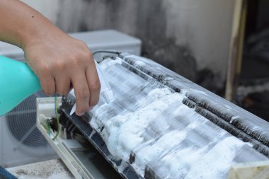 Klima temizleme konsepti. İşçi, havalandırmayı temizleyen kirli bir makine. Profesyonel Temizlik servisi ve bakımı ile klima temizleme, filtreleri tamir ve temizleme.