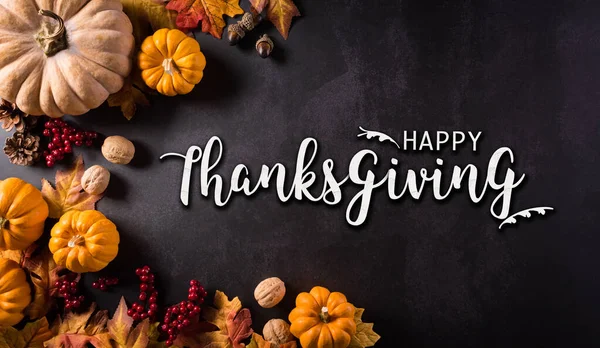 Şükran Günleri ve sonbahar kompozisyonu. Balkabağı, pamuk çiçekleri ve sonbahar yaprakları üzerinde koyu taş arkaplan ile metin.