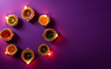 Mutlu Diwaliler - Dipavali sırasında Clay Diya lambaları yandı, Hindu ışık festivali kutlaması. Mor arka planda renkli geleneksel gaz lambası diya