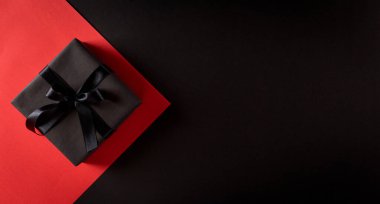 Siyah ve kırmızı arkaplanda siyah kurdeleli Noel kutularının üst görüntüsü metin için kopyalama alanı ile. Kara Cuma kompozisyonu.