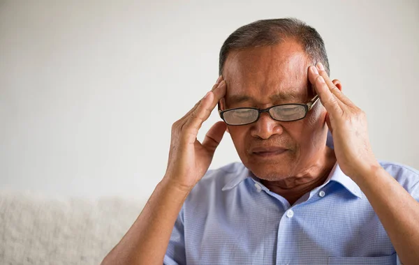 アジア系の老人はソファに座り 家で頭痛がする シニアヘルスケアコンセプト — ストック写真