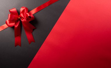 Kırmızı kurdele dekorasyonunun üst görüntüsü siyah ve kırmızı arka planda. Alışveriş konsepti boks günü ve Kara Cuma kompozisyonu.