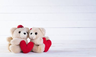 Sevgililer günün kutlu olsun ve beyaz ahşap arka planda ayı olan el yapımı kırmızı kalplerden yapılan aşk dekorasyonu konseptin..