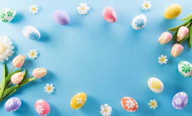 Mutlu Paskalyalar! Renkli Paskalya yumurtaları. Pastel mavi arka planda çiçekler..