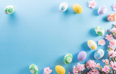 Mutlu Paskalyalar! Renkli Paskalya yumurtaları. Pastel mavi arka planda çiçekler..