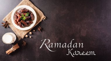 Dekorasyonun üst görünümü Ramazan Kareem, koyu taş arkaplanda metni bulunan meyve ve süt tarihleri.