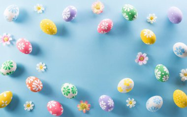 Mutlu Paskalyalar! Renkli Paskalya yumurtaları. Pastel mavi arka planda çiçekler..