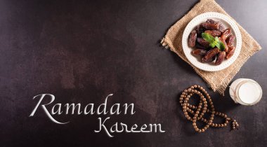 Dekorasyonun üst görünümü Ramazan Kareem, koyu taş arkaplanda metni bulunan meyve ve süt tarihleri.