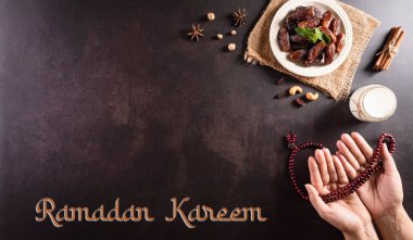 Ramazan Kareem arkaplan kavramı, Ellerinde hurma, süt ve koyu taşlı arka plandaki yazı olan tespih boncukları..
