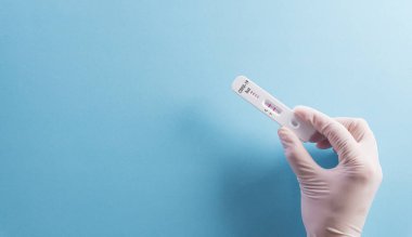 Doktorun elinde mavi arka planda kovid 19 hızlı antijen testi var. Dünya çapında koronavirüs salgını konsepti.
