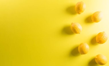 Pastel sarısı arka planda limon ya da limondan yapılmış yaz kompozisyonu. Meyve asgari konsept. Düz konum, üst görünüm, kopyalama alanı.