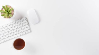 Üst kattaki ofis masasında yatıyordu. Klavyeli çalışma alanı, ofis malzemeleri ve beyaz arka planda fotokopi alanı olan kahve fincanı.