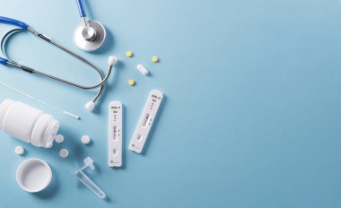 Covid-19 hızlı antijen testi, steteskop ve mavi arka planda ilaç. Dünya çapında koronavirüs salgını konsepti.