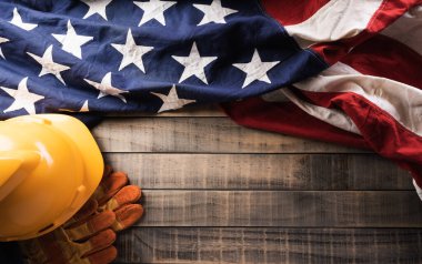 İşçi Bayramı konseptin kutlu olsun. Koyu ahşap arka planda farklı inşaat araçlarına sahip Amerikan bayrağı.