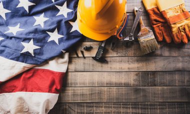 Happy Labor day concept. American flag with different construction tools on dark wooden background.