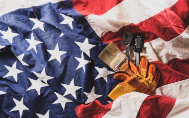 Happy Labor day concept. American flag with different construction tools on dark wooden background.