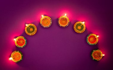 Mutlu Diwaliler - Dipavali sırasında Clay Diya lambaları yandı, Hindu ışık festivali kutlaması. Mor arka planda renkli geleneksel gaz lambası diya