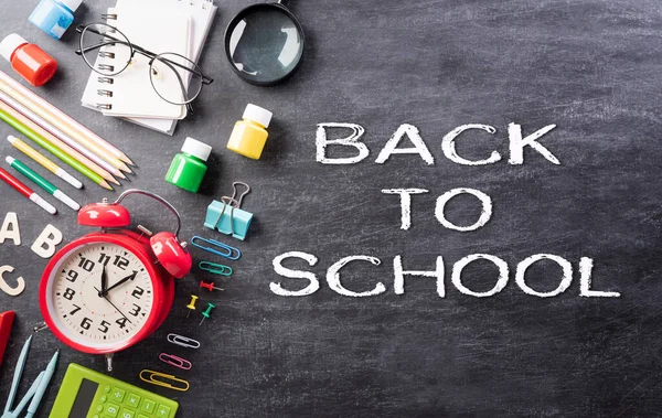 Eğitim ya da okula dönüş konsepti. Renkli okul malzemelerinin kitaplarla, renkli kalemlerle, hesap makinesiyle, kalemle, kesiciyle ve arka plandaki kliplerle en iyi görünümü.