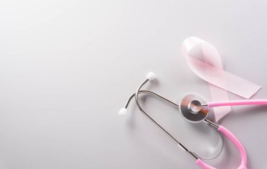 Pink ribbon and stethoscope on paper background for supporting breast cancer awareness month campaign.