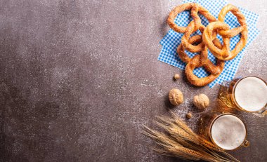 Oktoberfest festival decoration symbols made from Pretzel loaf, beer, sausage, potato chips and Bavarian white and blue fabric on dark stone background.