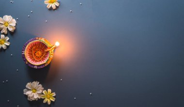 Happy Diwali - Clay Diya lamps lit during Diwali, Hindu festival of lights celebration. Colorful traditional oil lamp diya on blue background
