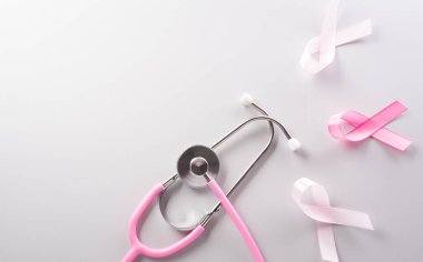Pink ribbon and stethoscope on paper background for supporting breast cancer awareness month campaign.