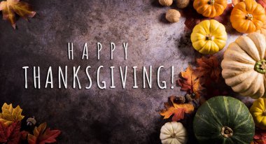 Sonbahar yaprakları, balkabağı ve mevsimsel sonbahar dekoru ve koyu taş arka plandaki yazı ile Şükran Günü arkaplan kavramı.