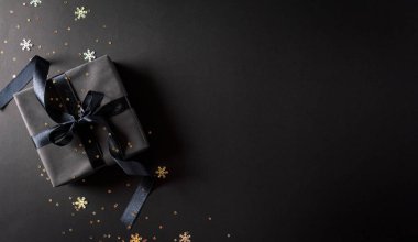 Siyah arkaplanda siyah kurdele ve metin için fotokopi alanı olan siyah Noel hediye kutularının üst görüntüsü. Kara Cuma kompozisyonu.