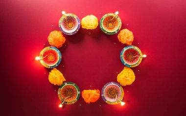 Happy Diwali - Clay Diya lamps lit during Diwali, Hindu festival of lights celebration. Colorful traditional oil lamp diya on red background