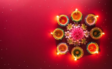 Happy Diwali - Clay Diya lamps lit during Diwali, Hindu festival of lights celebration. Colorful traditional oil lamp diya on red background