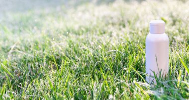Çimlerin üzerinde beyaz bir şişe var. Buz ve çiy damlaları var. Sabah tazeliğinin kokusu. Pankart