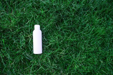 Çimlerin üzerinde buz ve çiy damlalarıyla beyaz bir şişe uzanıyor. Sabah taze soğuk aroması. düz yat