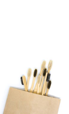 Çevre dostu bambu diş fırçaları beyaz bir arka planda bir kese kağıdının içinde yatıyor. Düz yerde, üst tarafta. Uzayı kopyala Sıfır atık kişisel bakım ürünü, diş bakımı.