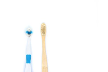Çevre dostu bir bambu diş fırçası beyaz arka planda eski bir plastik fırçanın yanında yatar. Düz yerde, üst tarafta. Uzayı kopyala Sıfır atık kişisel bakım ürünü, diş bakımı