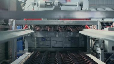 Çatı ve binaların ön cephesi için üretim malzemeleri üreten fabrikada metal levha oluşturma makinesi. Metal döşeme ve yan kaplama üretim sürecinde olan metal üretim hattı