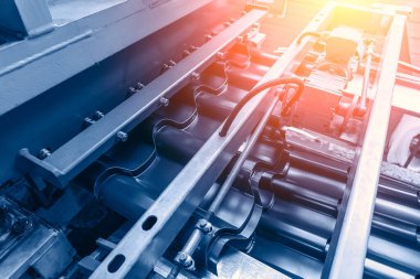 Endüstriyel geçmiş. Fabrikada metal levha, makine taşıma bandı oluşturur. Çatı kiremit imalatı