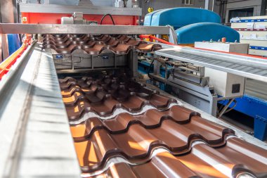 Galvanizli ve boyalı çelikten yapılmış kahverengi metal kiremitler metal fabrikasında metal levha oluşturma makinesinde