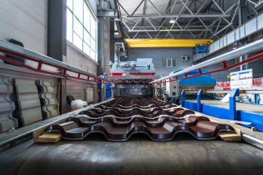 Galvanizli ve boyalı çelikten yapılmış kahverengi metal kiremitler metal fabrikasında metal levha oluşturma makinesinde