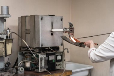 Özel laboratuvar ekipmanlarıyla metalurji tesisinde yanan alaşım numunesi test ediliyor.