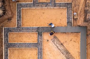 Çelik takviyesi üzerine sıvı beton ya da çimento döken işçiler, temel inşaatı sürecinde, hava manzarası