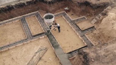 İnşaat sahasında çalışanlar beton dökerken takviyeyle birlikte. Sivil yapı temeline, hava manzarasına ıslak çimento dökülüyor