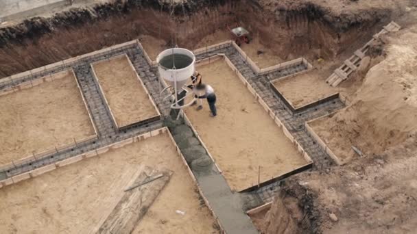 Planta de construcción con trabajadores vertiendo hormigón en encofrado con refuerzo. Cemento húmedo vierte a cimientos de edificios civiles, vista aérea — Vídeos de Stock