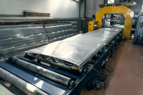 Förderband oder Linie mit fertig verpackten Dachziegeln aus Metall. Industrielle Produktion von Dächern auf automatisierten Anlagen — Stockfoto
